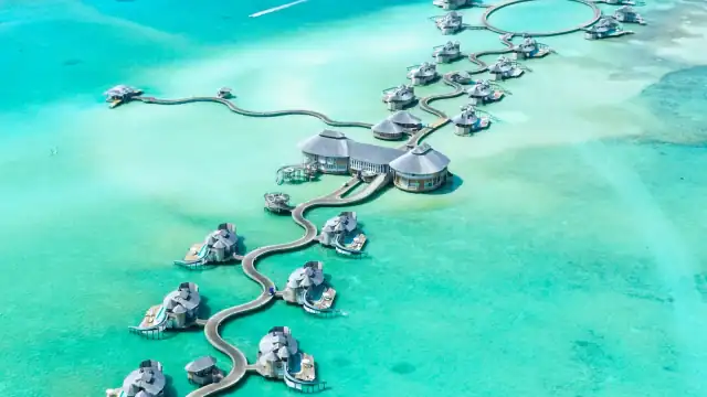 Overwater villas and clear lagoon water in the Maldives at sunset
